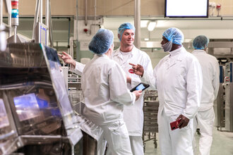 Foto von 3 Mitarbeitern in der Produktion bei Wewalka, die gemeinsam an einer Lösung bei einer Steuerungseinheit der Maschine für Frischteige arbeiten